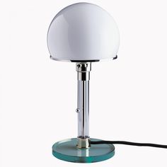 a lamp that is on top of a glass base with a cord attached to it