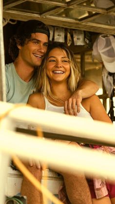 a man and woman are sitting on the back of a boat smiling at the camera