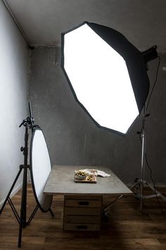 a photo studio setup up with light and lighting equipment in front of a table on a wooden floor