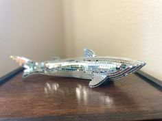 a metal fish sitting on top of a wooden table