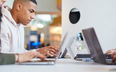 two people sitting at a table using laptops