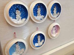 six snowmen are in the middle of small bowls on a wall with magnets attached to them