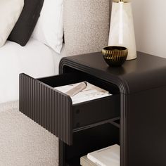 a night stand with magazines and a vase on the end table in front of it