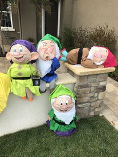 three garden gnomes sitting on top of a stone wall