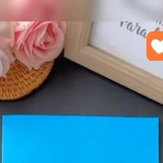 a pink rose sitting on top of a table next to a blue card and a pair of shoes