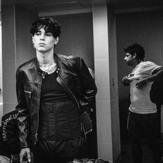 a man standing in front of a mirror wearing a leather jacket