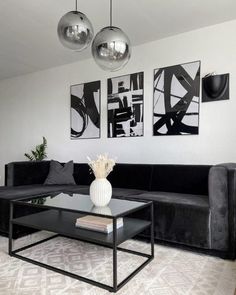 a living room with black couches and art hanging on the wall above it's coffee table