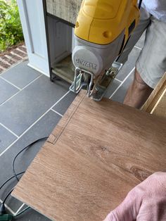 a person using a power drill to attach a piece of wood on top of a tile floor