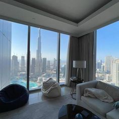 a living room filled with furniture and tall buildings in the backround, looking out over the city