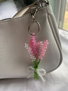 a white purse with pink flowers on the handle and a keychain attached to it