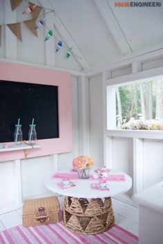 a room with pink and white decor on the walls, rugs and tables in front of a chalkboard