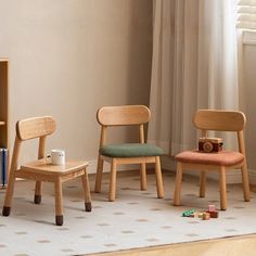 three children's wooden chairs sitting in front of a bookcase and bookshelf