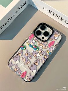 an iphone case with cartoon characters on it sitting next to a book and some books