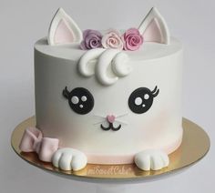 a white cat cake with pink roses on top