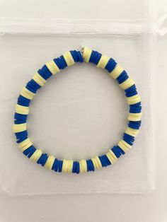 a blue and yellow beaded bracelet on a clear plastic case with a white background