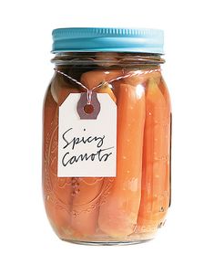 a jar filled with pickled carrots on top of a white table next to a blue lid