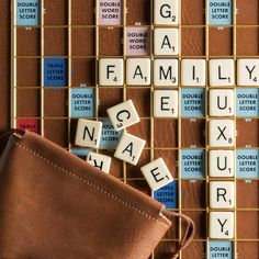 scrabble tiles spelling out family and letters on a board with leather pouch next to it