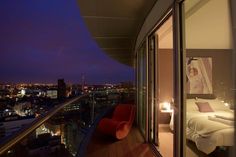 a bedroom with a balcony overlooking the city at night