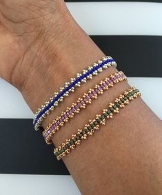 a woman's arm with four different colored bracelets on top of each other