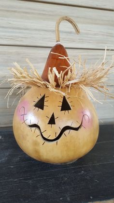 a wooden pumpkin with a face painted on it's side and an umbrella sticking out of the top