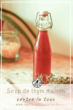 a bottle filled with red liquid sitting on top of a table next to a knife