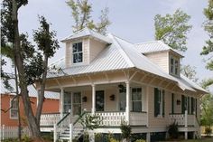 a small white house with porches on the front and side of it, surrounded by trees