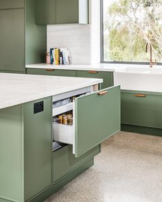 a kitchen with green cabinets and an open drawer in the middle, next to a window