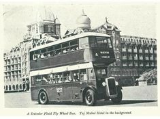 an old double decker bus driving down the street in front of a large building and clock tower