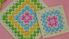 two square crocheted coasters sitting on top of a pink surface