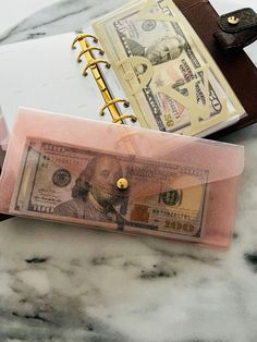 a note book and money are sitting on a marble counter top next to a wallet