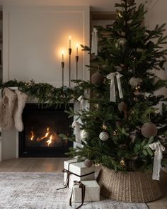 a decorated christmas tree in front of a fireplace with stockings on the mantels