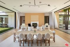 a dining room with white chairs and a table in front of an open living area