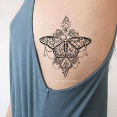 a butterfly tattoo on the back of a woman's upper arm, with intricate designs