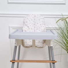 a baby high chair sitting next to a potted plant