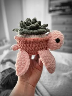 a hand holding a small crocheted turtle with a succulent plant on its back