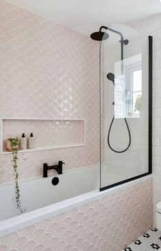 a white bath tub sitting under a window next to a sink and shower faucet