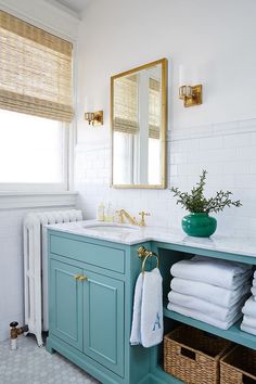 a bathroom with blue cabinets and white towels on the counter, along with a green vase filled with flowers