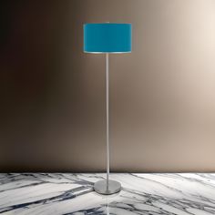 a floor lamp with a blue shade on it sitting on a marble countertop next to a brown wall