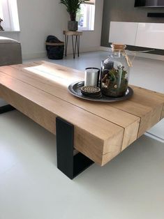 a coffee table with a bottle and some plants on it in the middle of a room