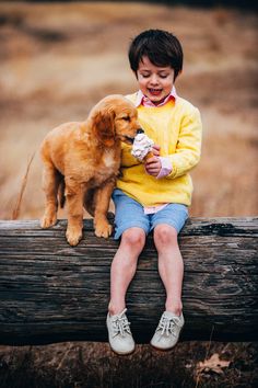 a little boy that is sitting on a log with a dog