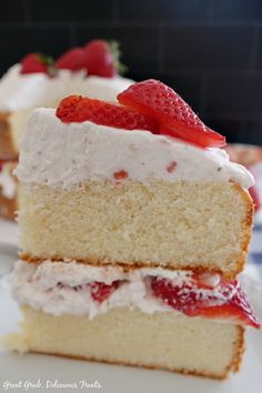 a piece of cake with white frosting and strawberries on top is sitting on a plate