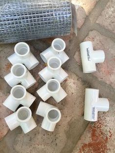 several white vases sitting on the ground next to a roll of wire mesh fence