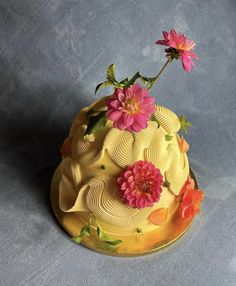 a yellow cake with pink flowers on top