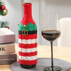 a wine bottle with a knitted christmas sweater on it next to a glass of wine