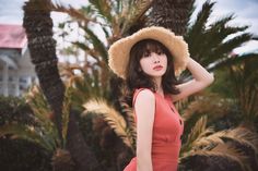 a woman wearing a hat standing in front of palm trees