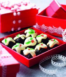 two red boxes filled with decorated cookies on top of a table next to white lace