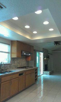 an empty kitchen with white tile flooring and wooden cabinets, along with recessed lighting