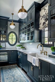 a large kitchen with blue cabinets and white counter tops, gold faucet lights