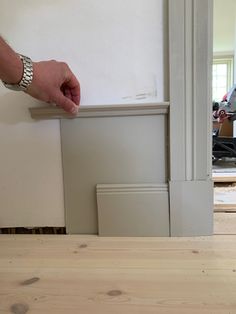 a person is holding the edge of a piece of wood in front of a door