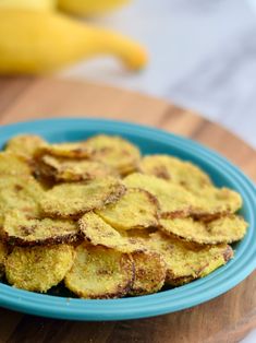 a blue bowl filled with fried food on top of a wooden table next to bananas